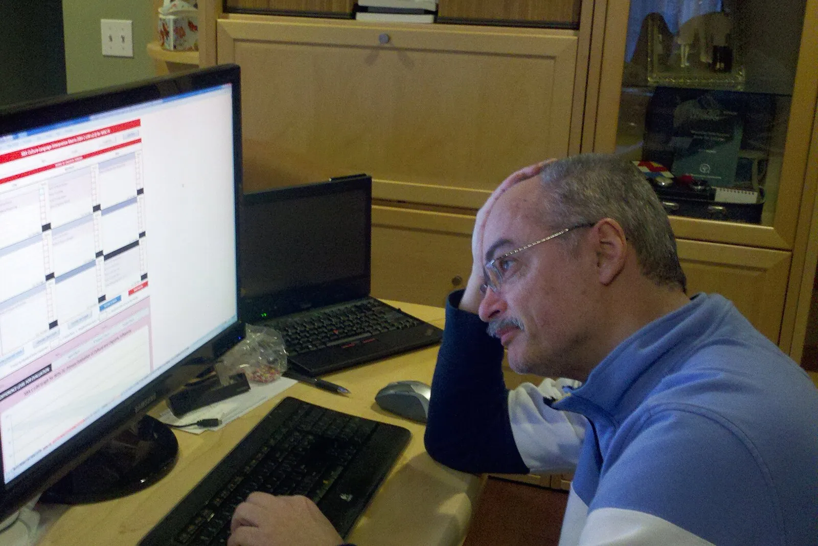 Dr. Ortiz at a computer with one hand on his head, looking at a large spreadsheet.